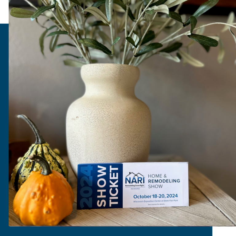 A vase with branches, two gourds, and a 2024 Home & Remodeling Show ticket on a wooden surface create an autumnal display.