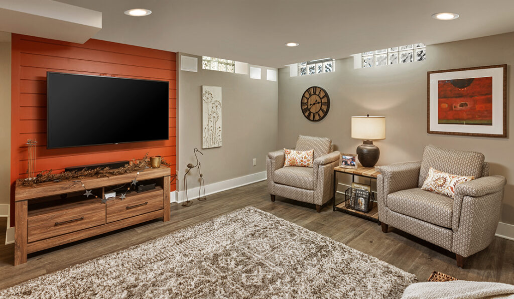 Luxurious basement remodel by S.J. Janis. The room features a large entertainment/media area, seating, and a darts board in the corner.