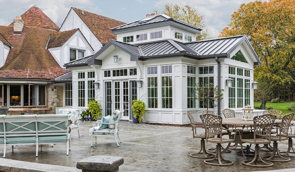 Large sunroom addition built onto the back of a home, surrounded by large patio and trees.