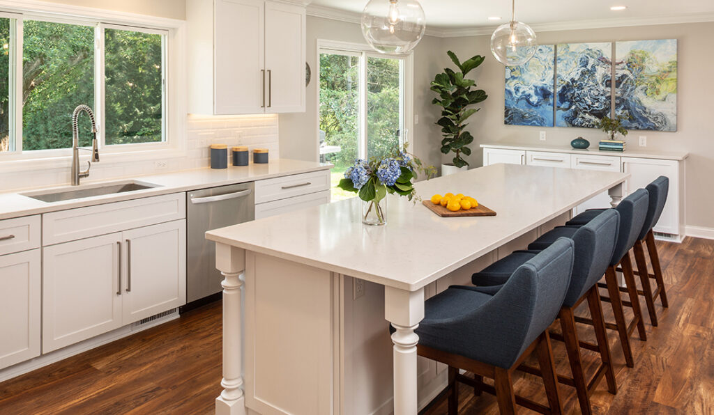 Recently remodeled kitchen in Brookfield featuring new flooring, white stone countertops, fixtures, and a large island with seating.