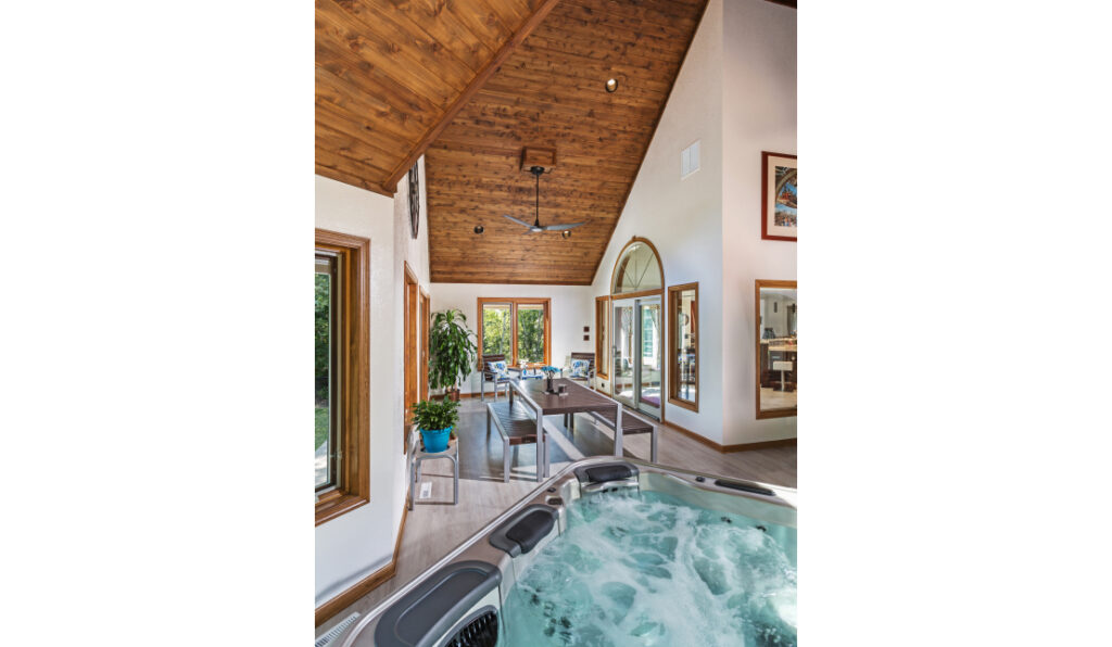 A newly built spa room complete with a hot tub, new flooring, high wood-paneled ceilings, and modern finishes.