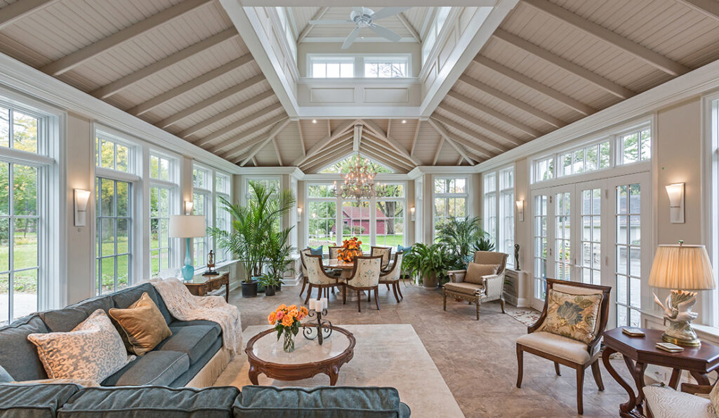 Large conservatory room addition. Features include tall ceilings, walls of windows, and ornate furniture.