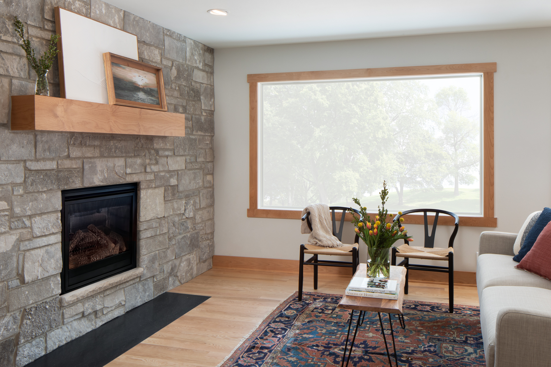 Remodeled living room with stone wall and fireplace