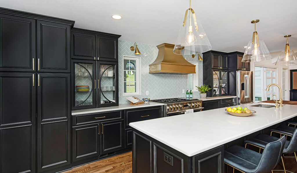 Freshly renovated kitchen with black cabinetry, wood flooring, and gold fixtures. White quartz countertops.