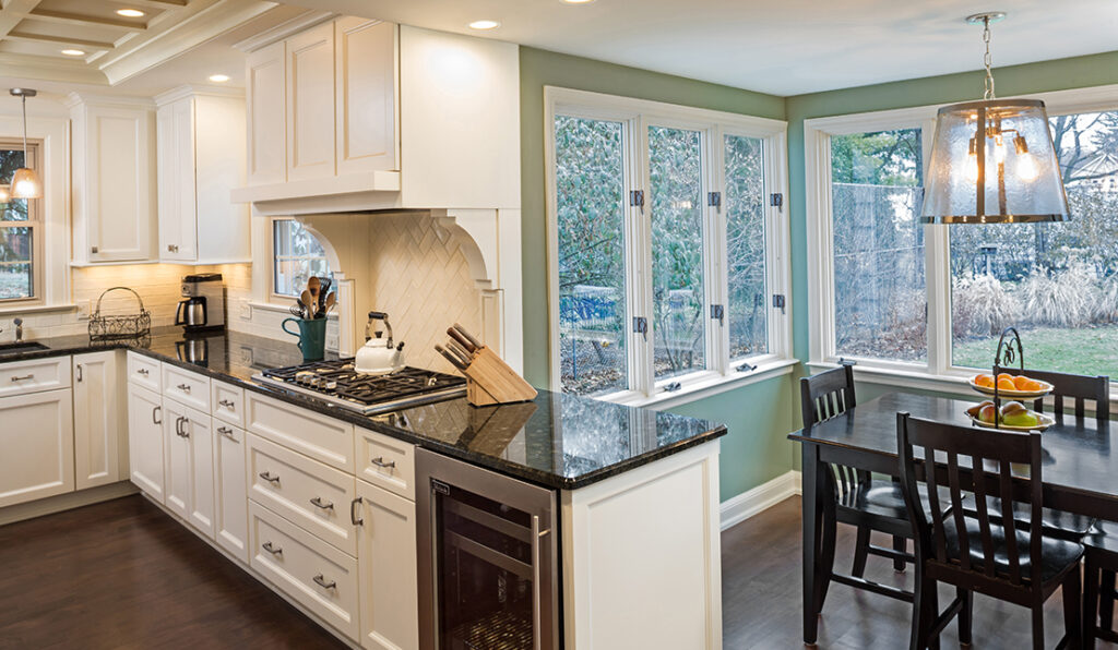 Remodeled kitchen featuring new black stone counters, white cabinetry, dark hardwood floors, and modern appliances.