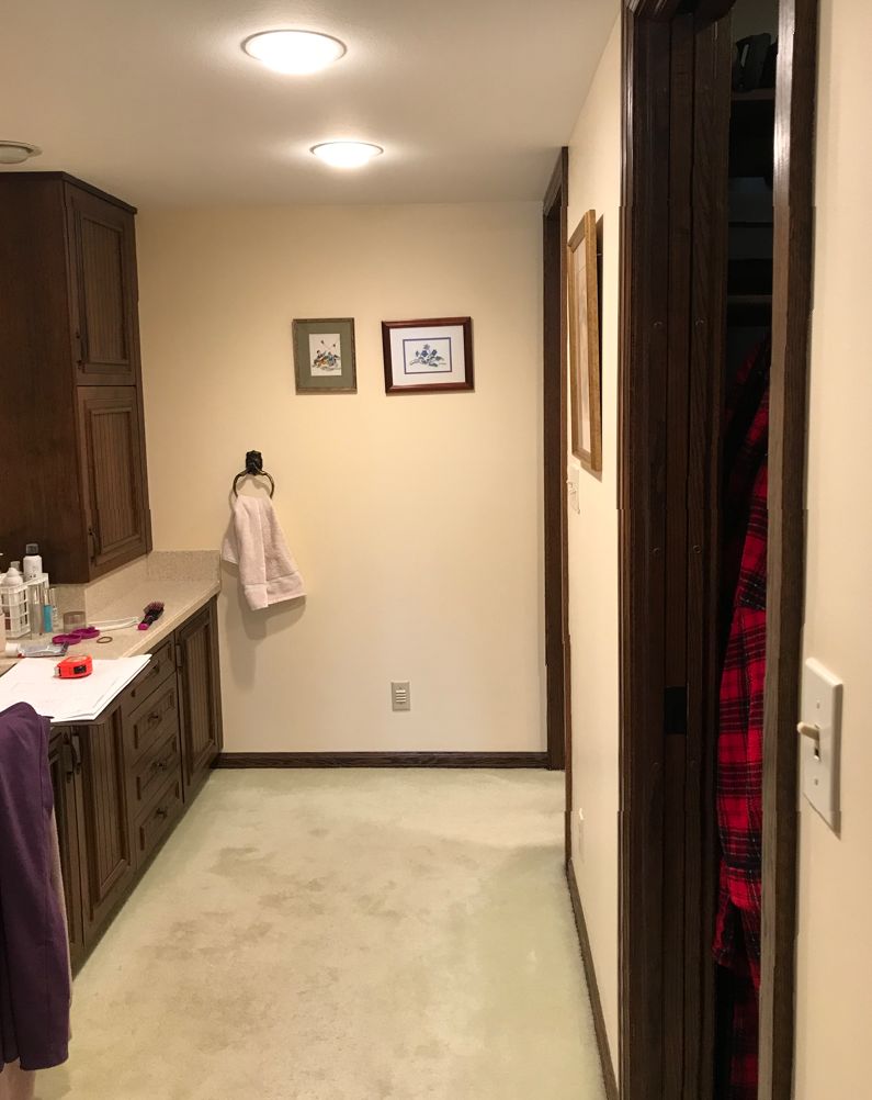 A cozy indoor hallway features wooden cabinets, framed artwork, a towel, and muted lighting, creating a warm, inviting atmosphere.