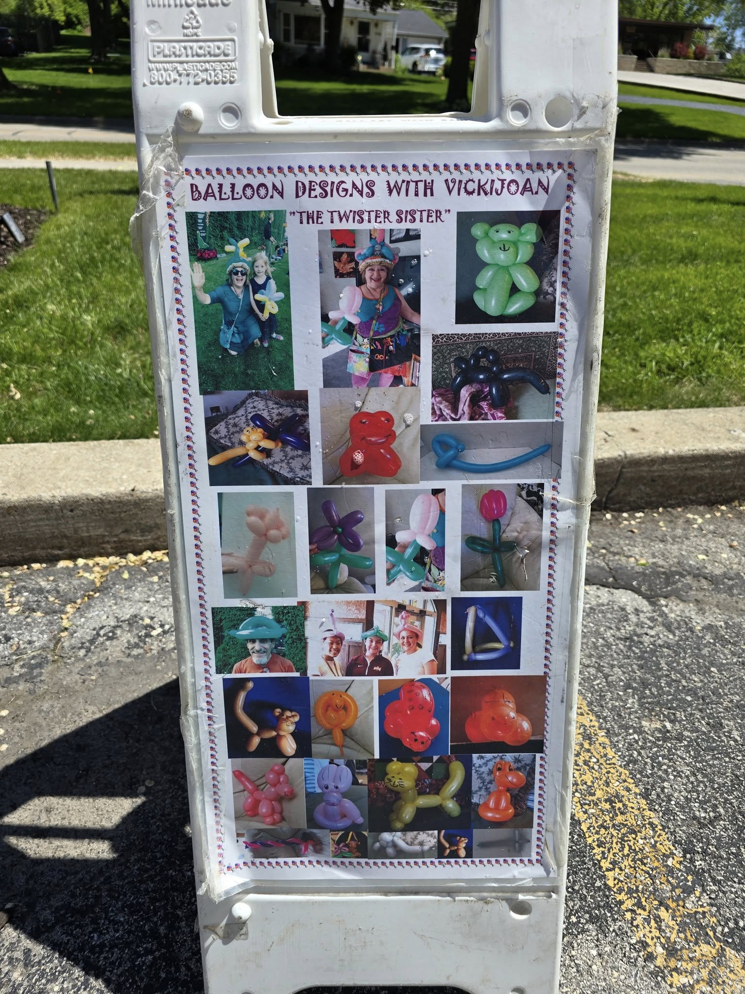 Poster on a sign displays colorful balloon art by VickiJoan, featuring animals and hats. It's titled "Balloon Designs with VickiJoan".