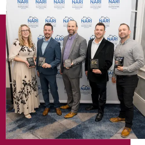 Five people holding awards stand in front of a branded backdrop, posing for a group photo at an event.
