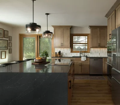 Modern kitchen with wooden cabinets, black countertops, and stainless steel appliances. Large windows provide natural light; wall art adds decorative touches.