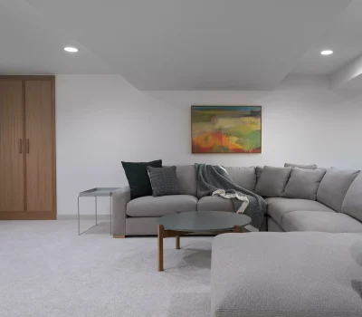 A cozy, modern living room with a large gray sectional sofa, abstract painting, and wooden cabinets, creating a simple and inviting atmosphere.