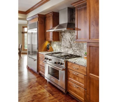 Modern kitchen with stainless steel appliances, granite countertops, and wooden cabinets. Bright, open space with a dining area visible in the background.