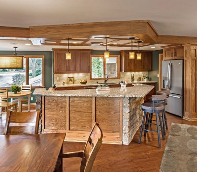 Spacious kitchen and dining area with wood cabinets, granite countertops, pendant lights, and a central island. Large windows offer a garden view.