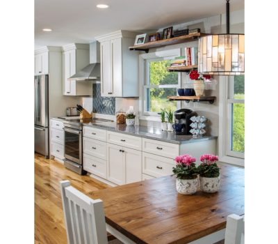 Bright, modern kitchen with white cabinets, stainless steel appliances, and wooden accents. A large window overlooks greenery, brightening the cozy space.