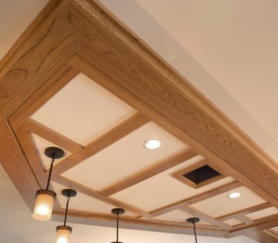 A wooden coffered ceiling with recessed lighting and pendant lights adds elegance to the space. The intricate grid design features a warm finish.
